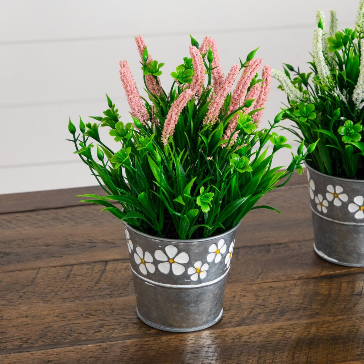 two metal buckets with flowers on a table