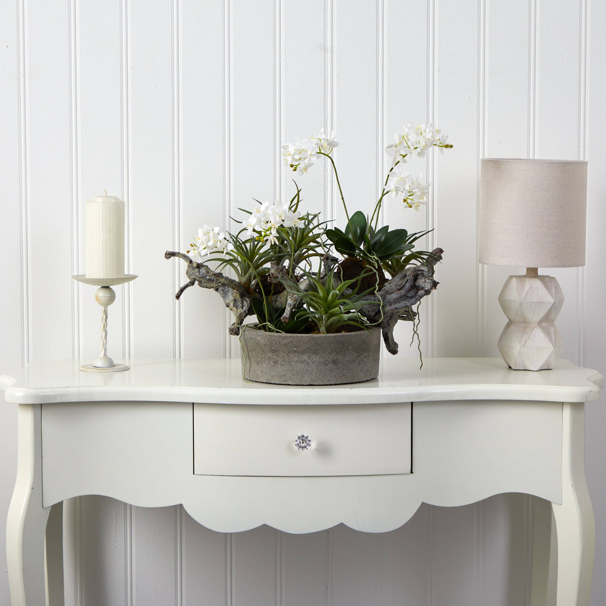 a white table with a plant and a candle on it