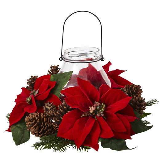 a glass candle holder with red flowers and pine cones