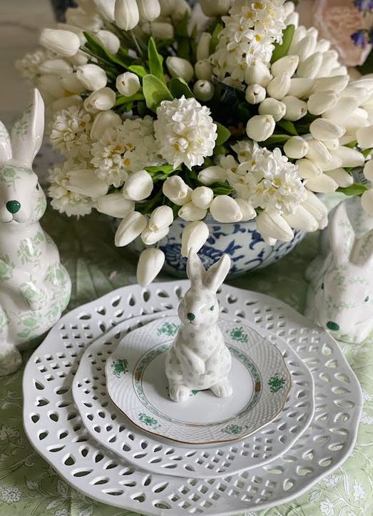 a white and green bunny figurine on a plate with white flowers