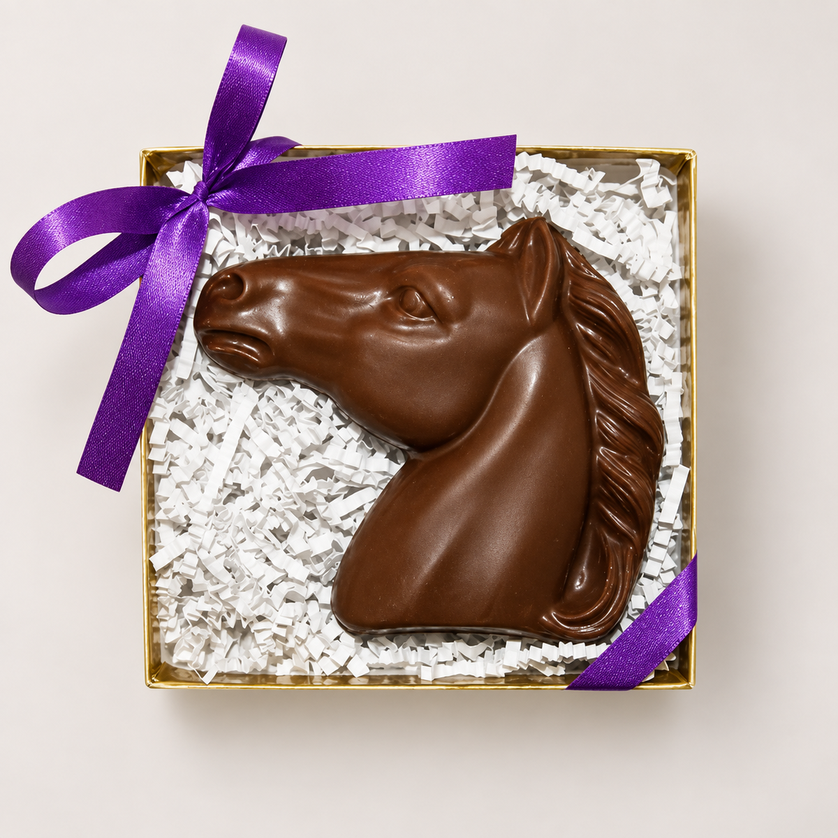 a chocolate horse head in a box with a purple ribbon