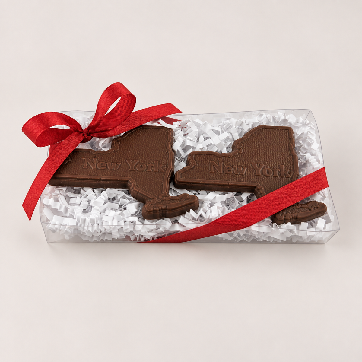a chocolate shaped like state shaped objects in a clear plastic box with a red ribbon