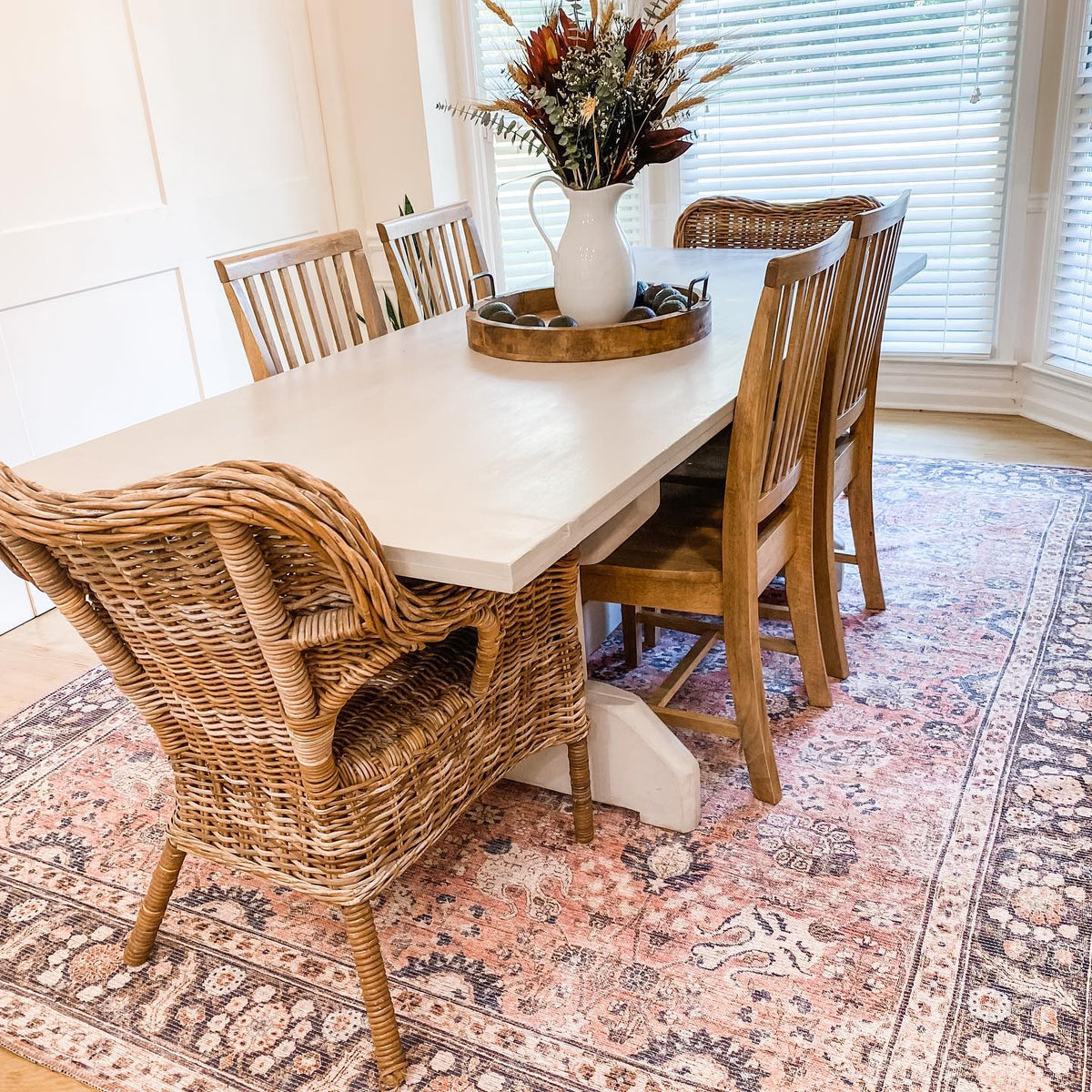 a table with chairs and a vase of flowers