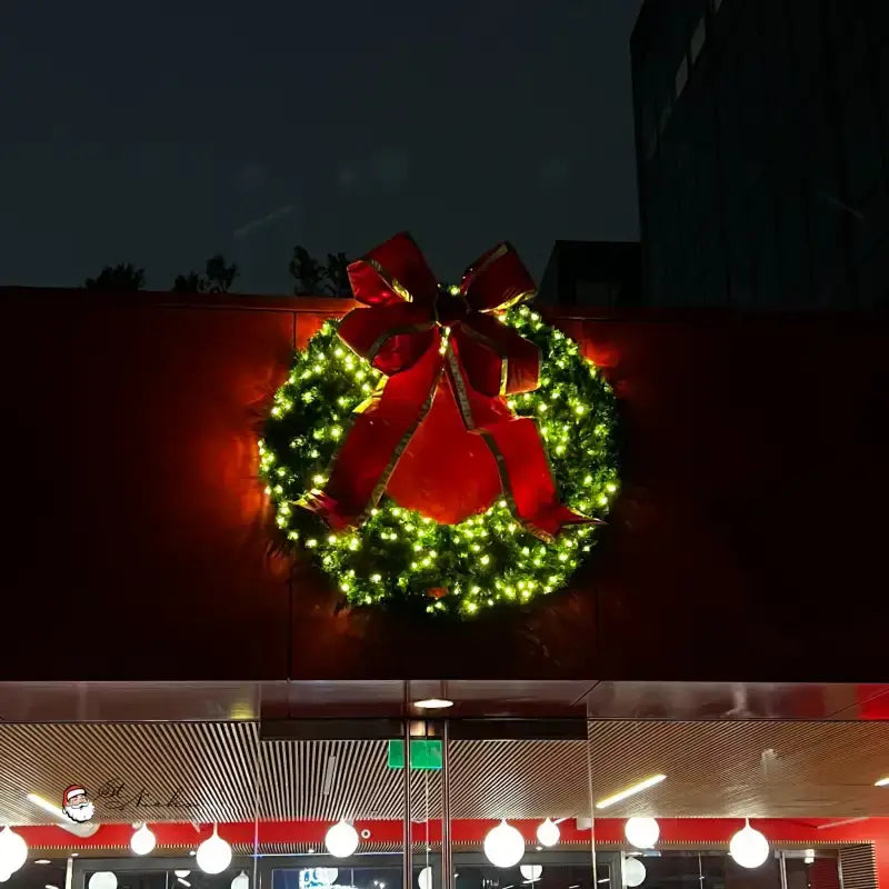 a large wreath with lights on the side of a building