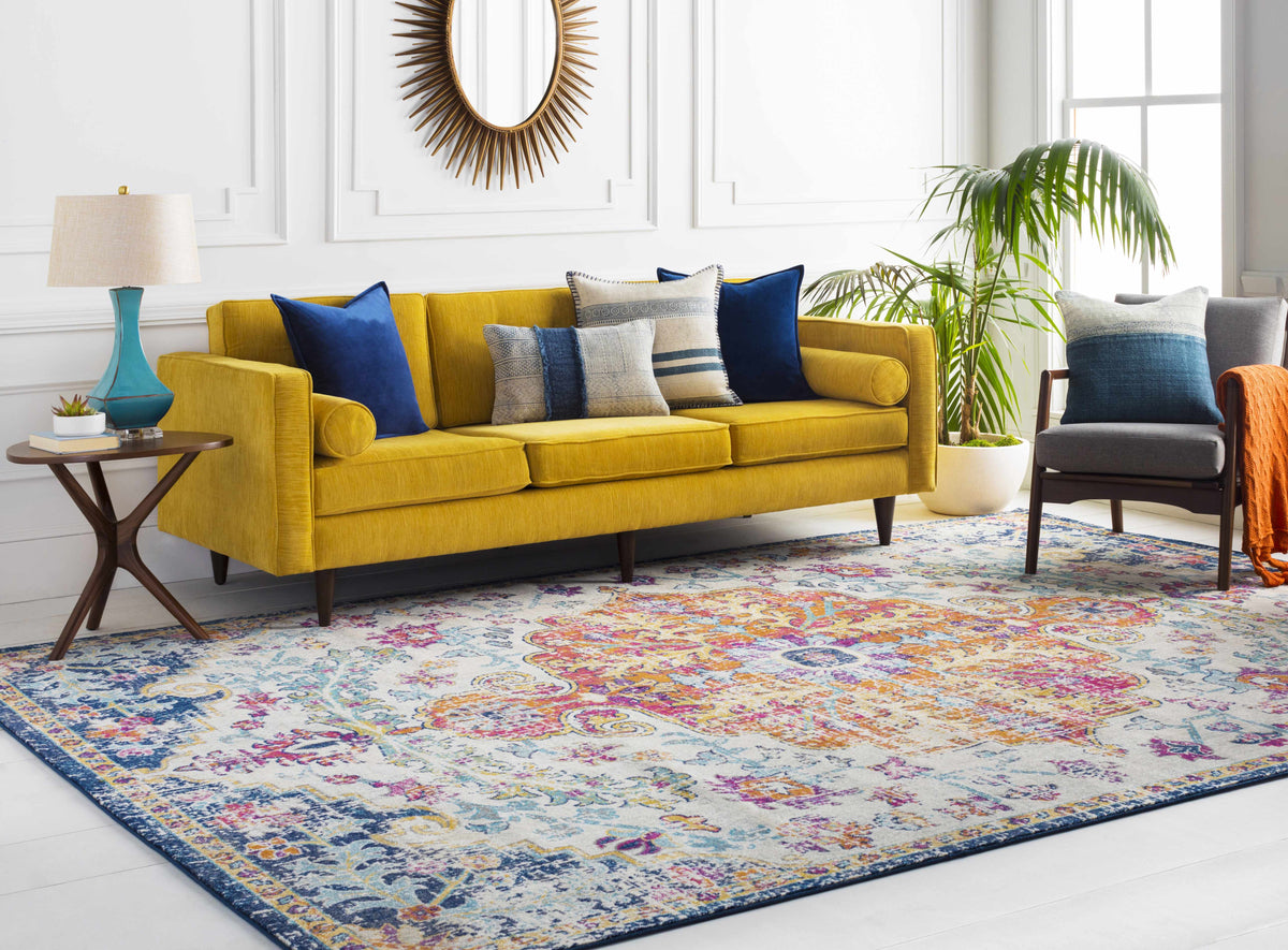 a yellow couch in a room with a colorful rug and a mirror