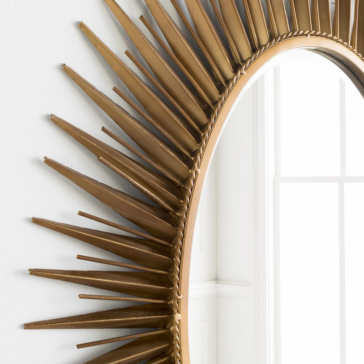 a gold mirror with spikes on the wall