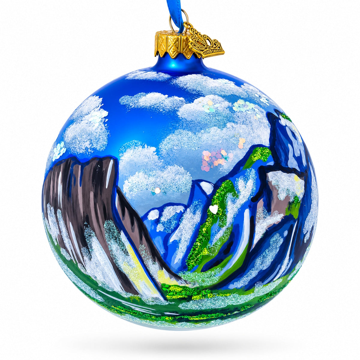 a blue and green ornament with mountains and clouds painted on it
