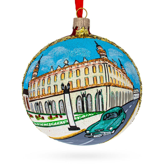 a christmas ornament with a painting of a building and a car