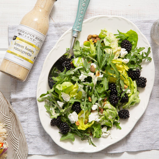 a plate of salad with a fork and a bottle of dressing