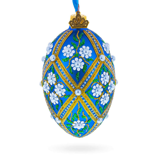 a blue decorated egg with white flowers and gold trim