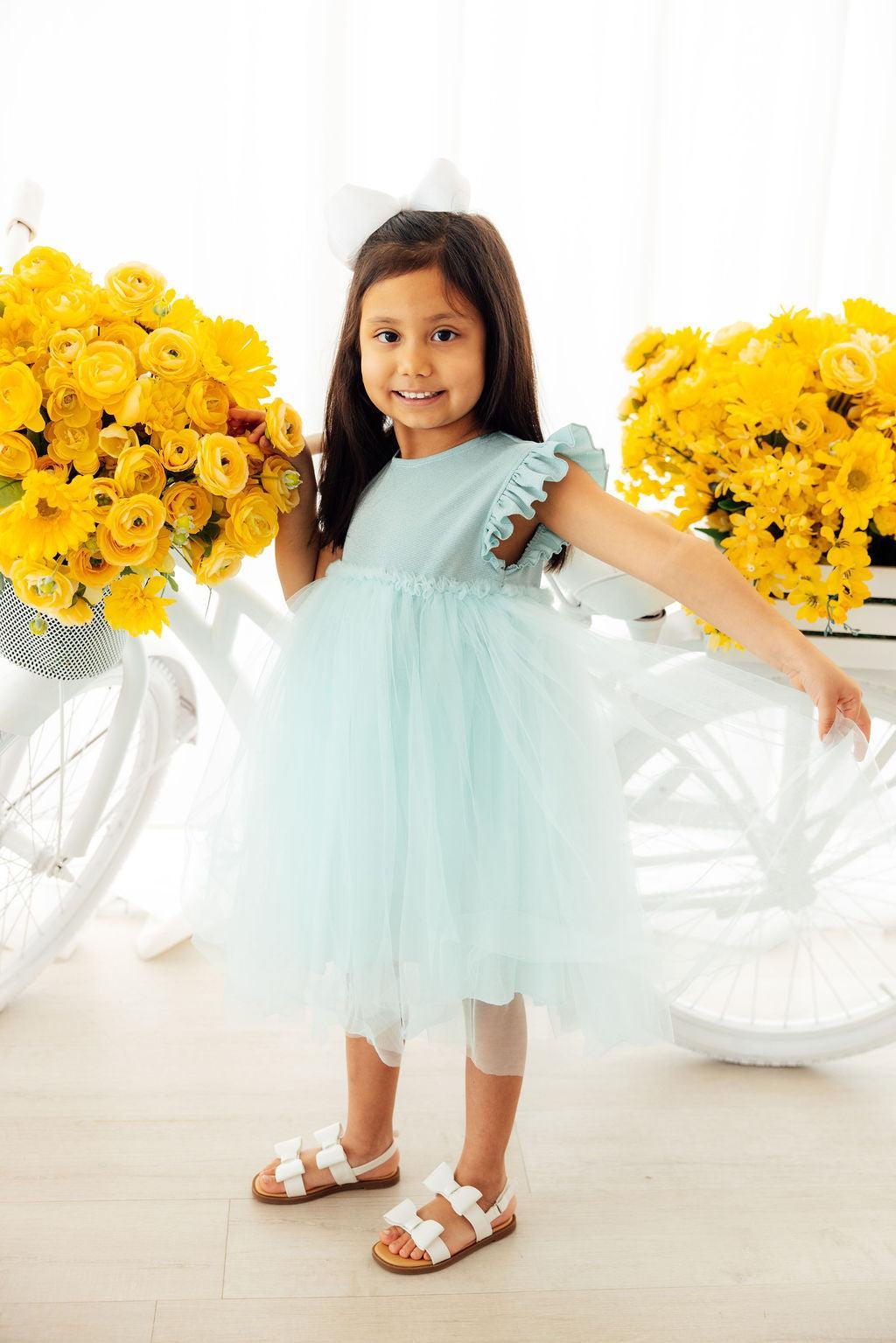 a girl in a blue dress with a bouquet of yellow flowers