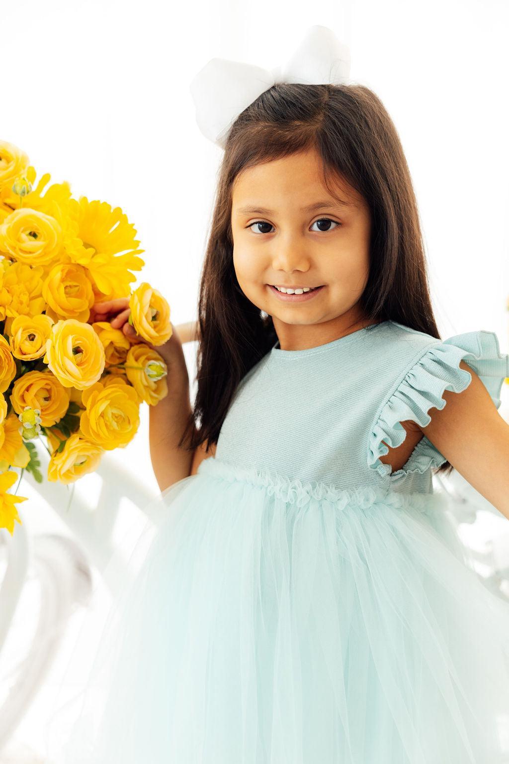 a girl in a dress holding flowers