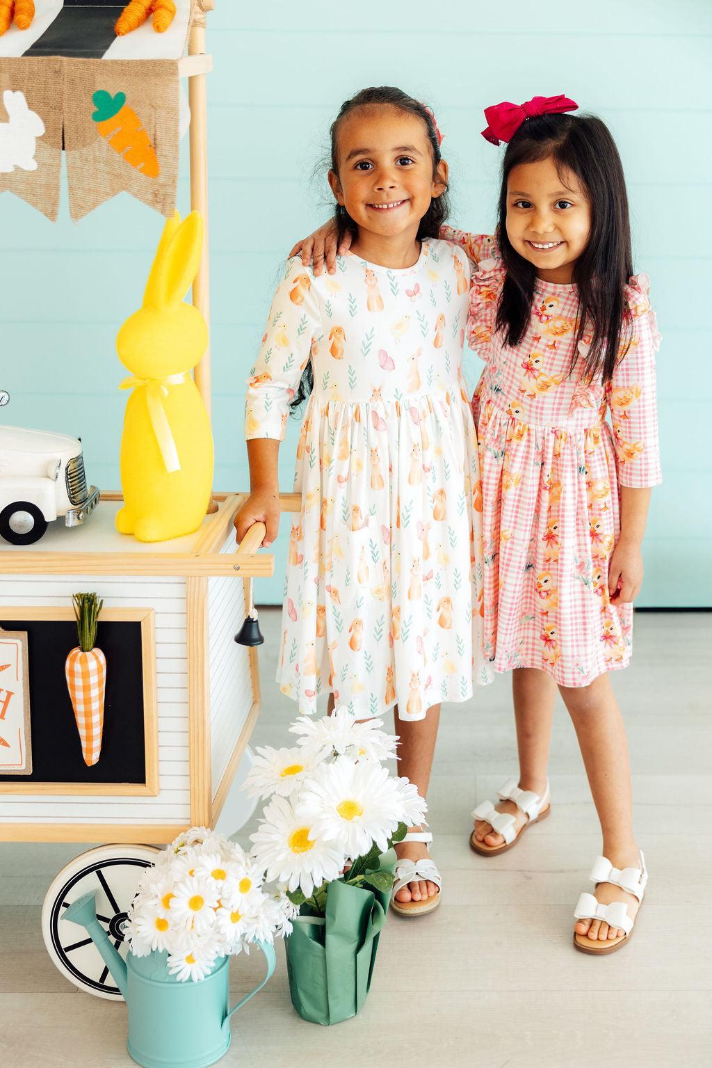 two girls standing next to a toy kitchen