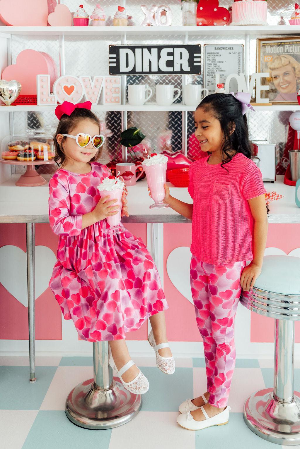 two girls holding drinks in front of a counter