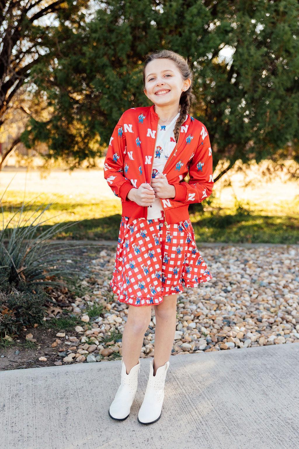 a girl in a red jacket and skirt