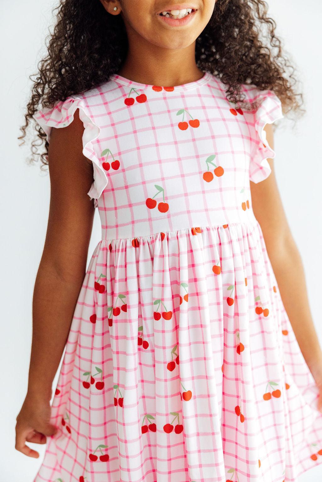 a girl wearing a pink and white checkered dress