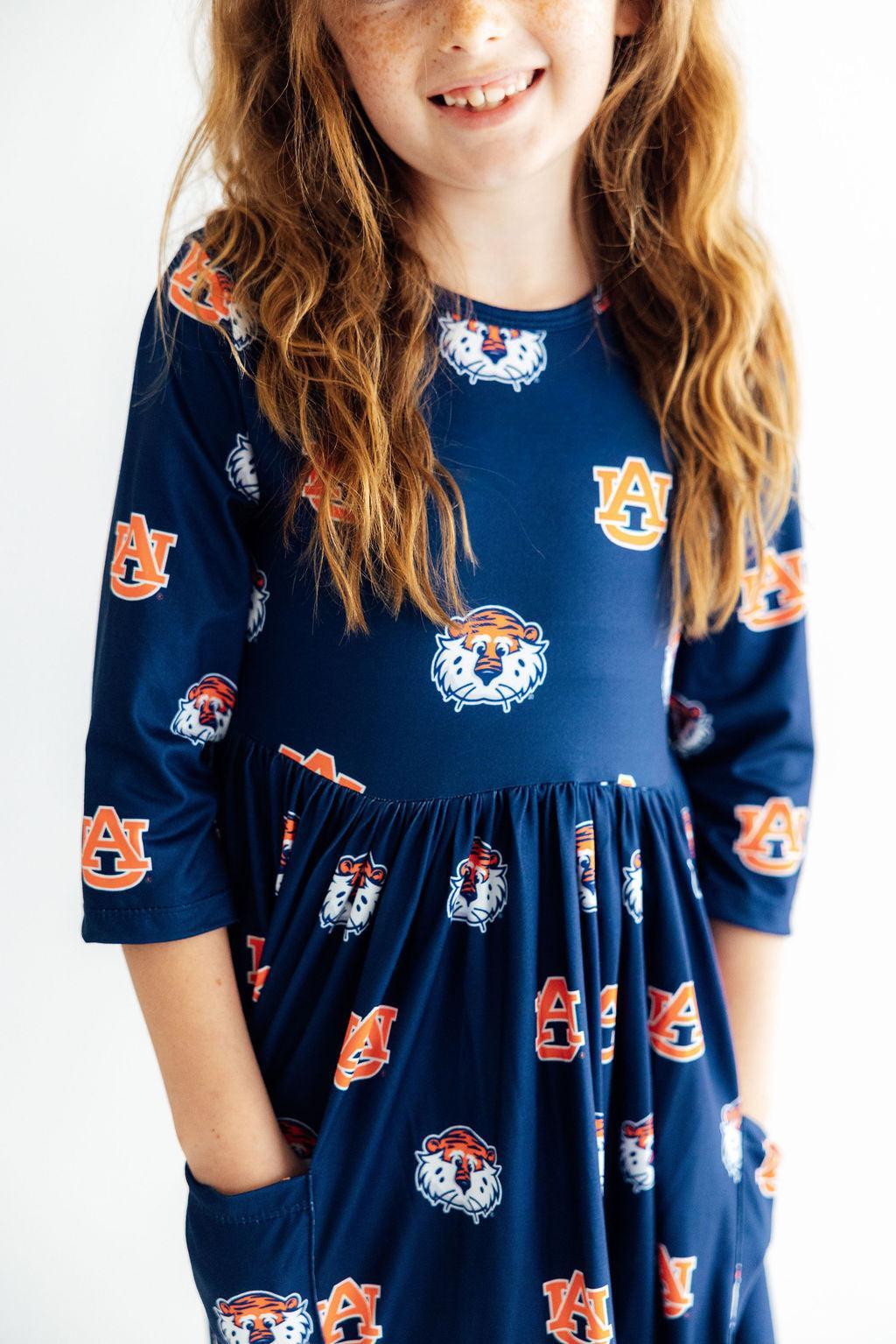 a girl wearing a blue dress with orange and white mascot designs