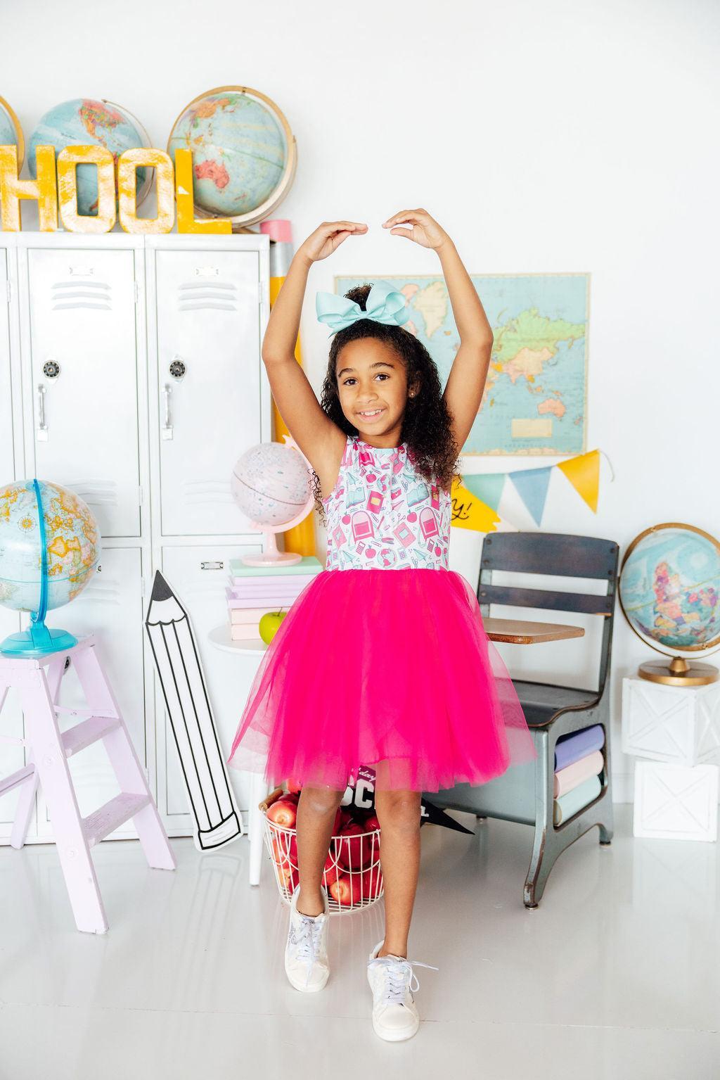 a girl in a pink tutu and a basket of fruit