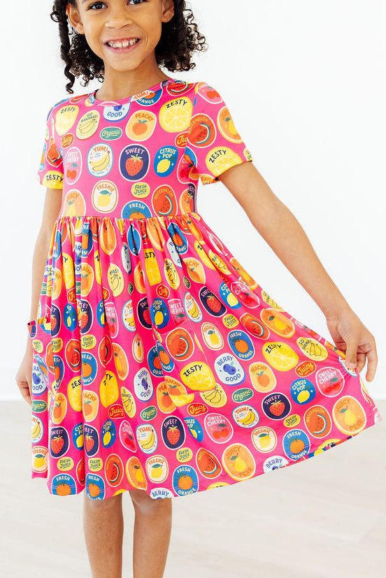 a girl wearing a dress with fruit print