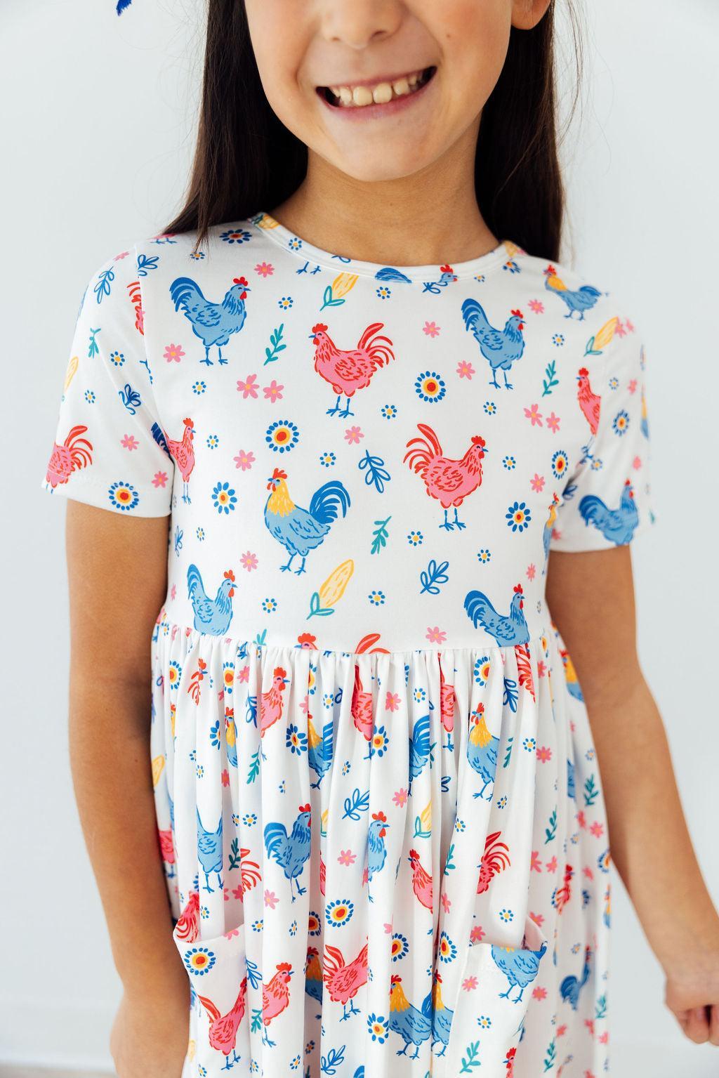 a girl wearing a dress with chickens and flowers