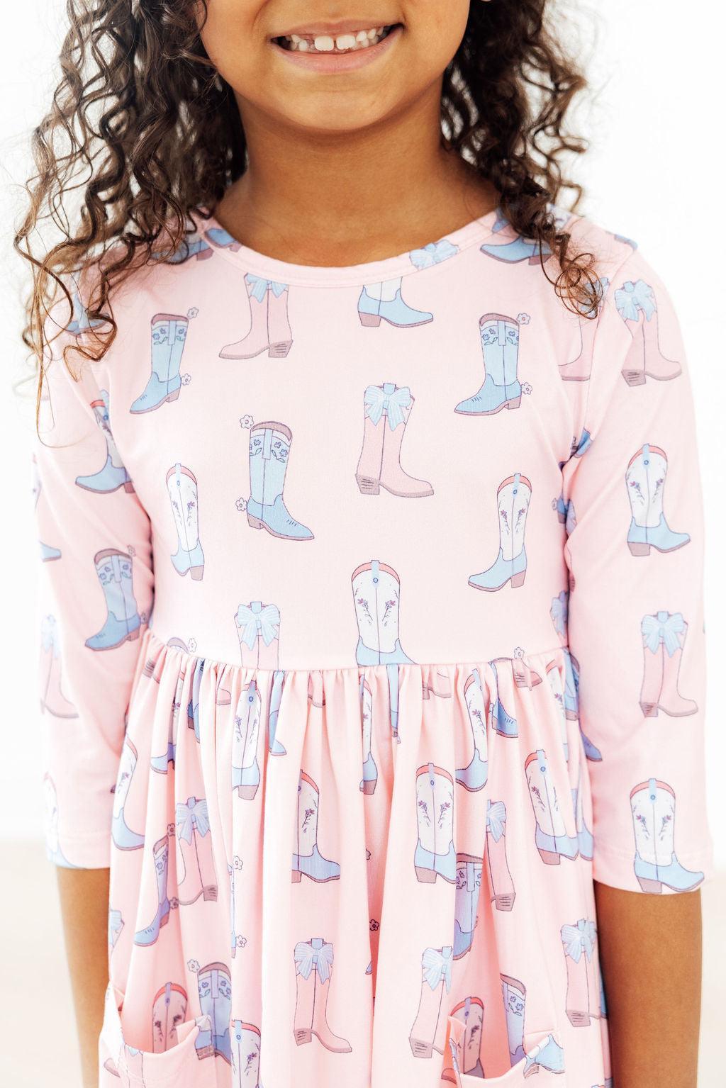 a girl wearing a pink dress with cowboy boots on it