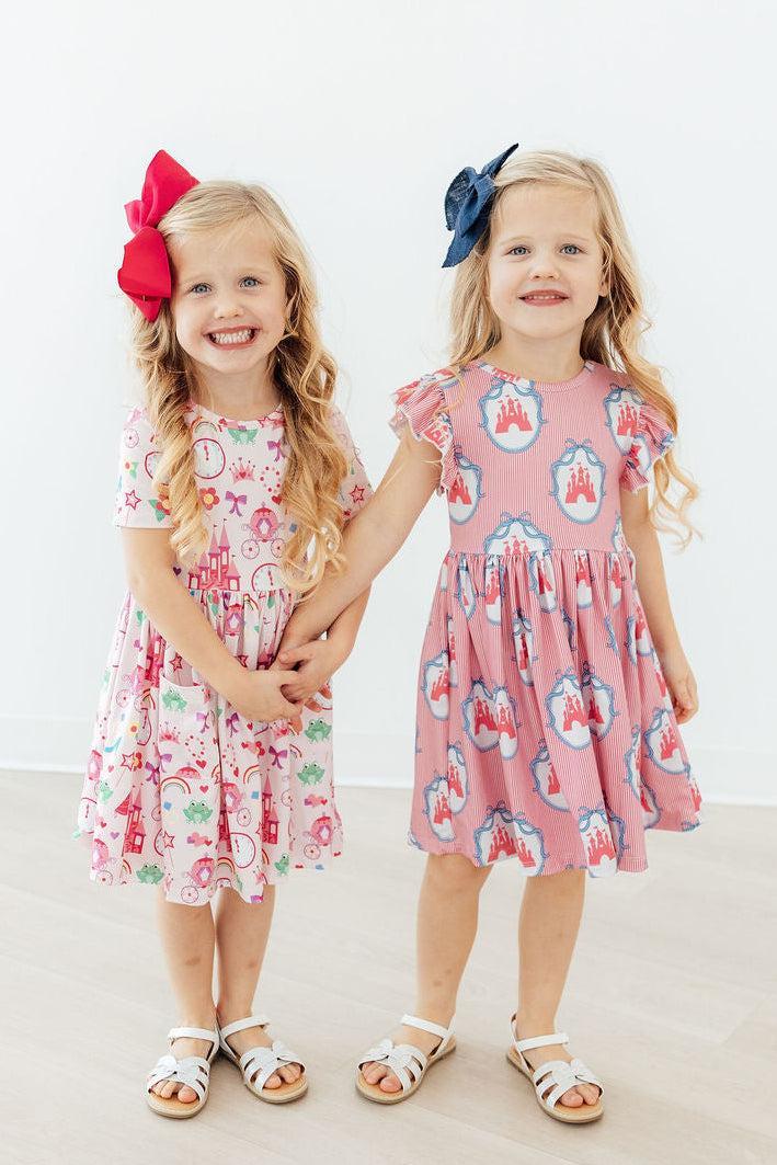 two girls wearing dresses and smiling