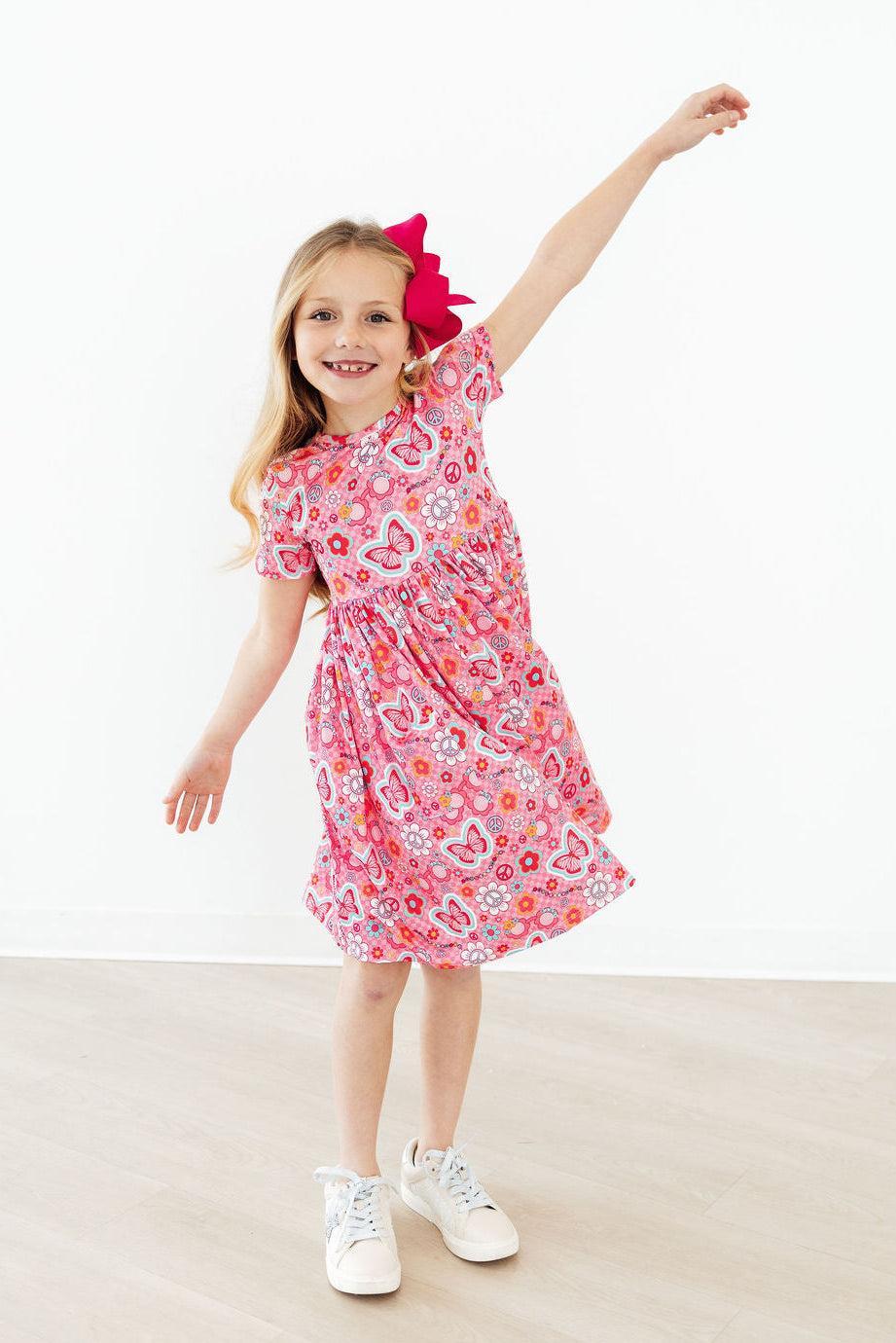 a girl in a pink dress with a red bow