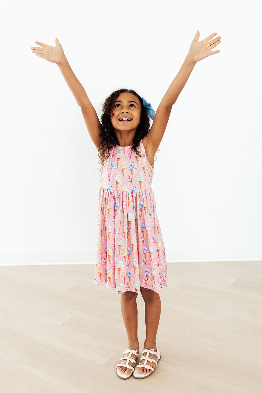 a girl in a pink dress with her arms up