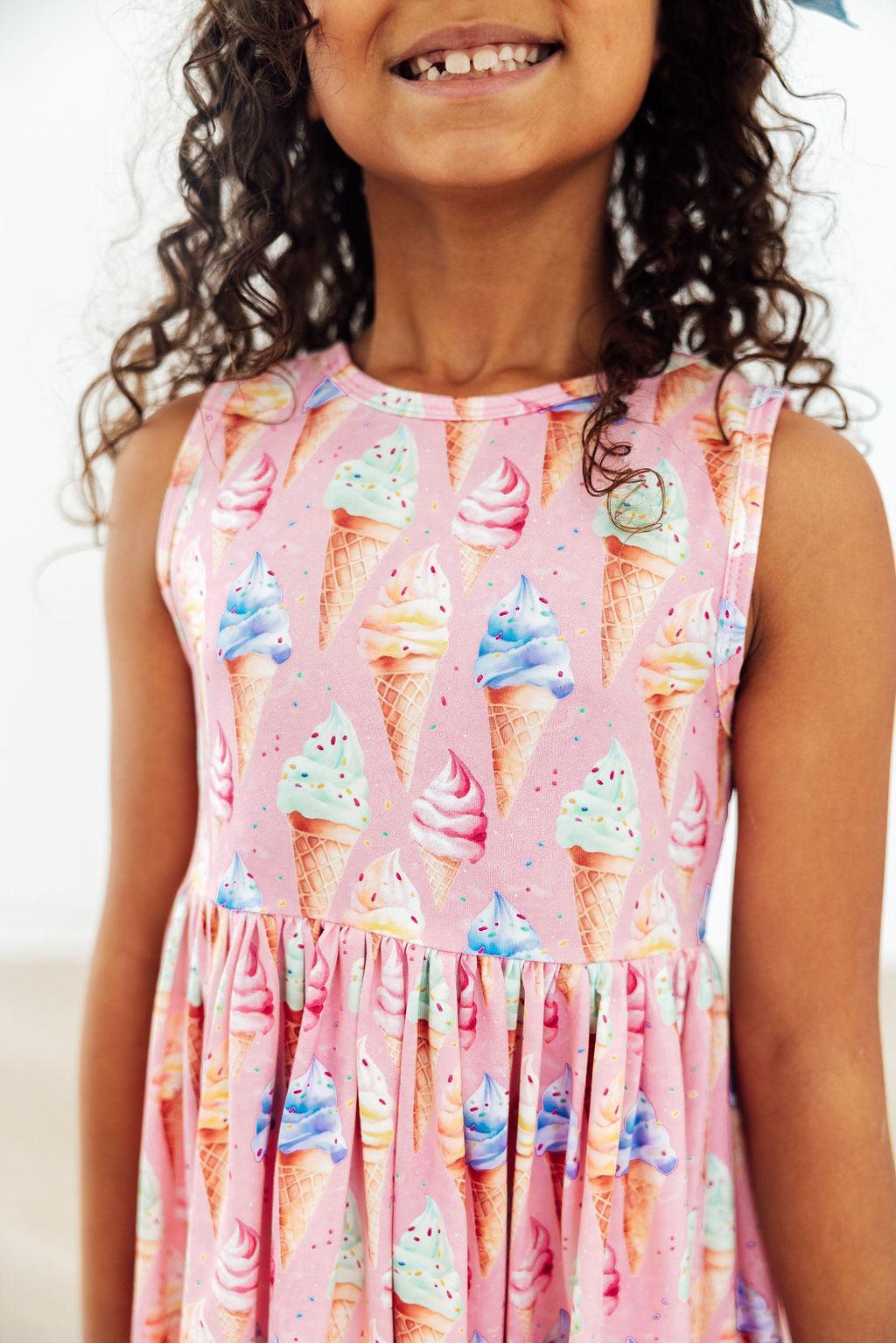 a girl wearing a pink dress with ice cream cones on it