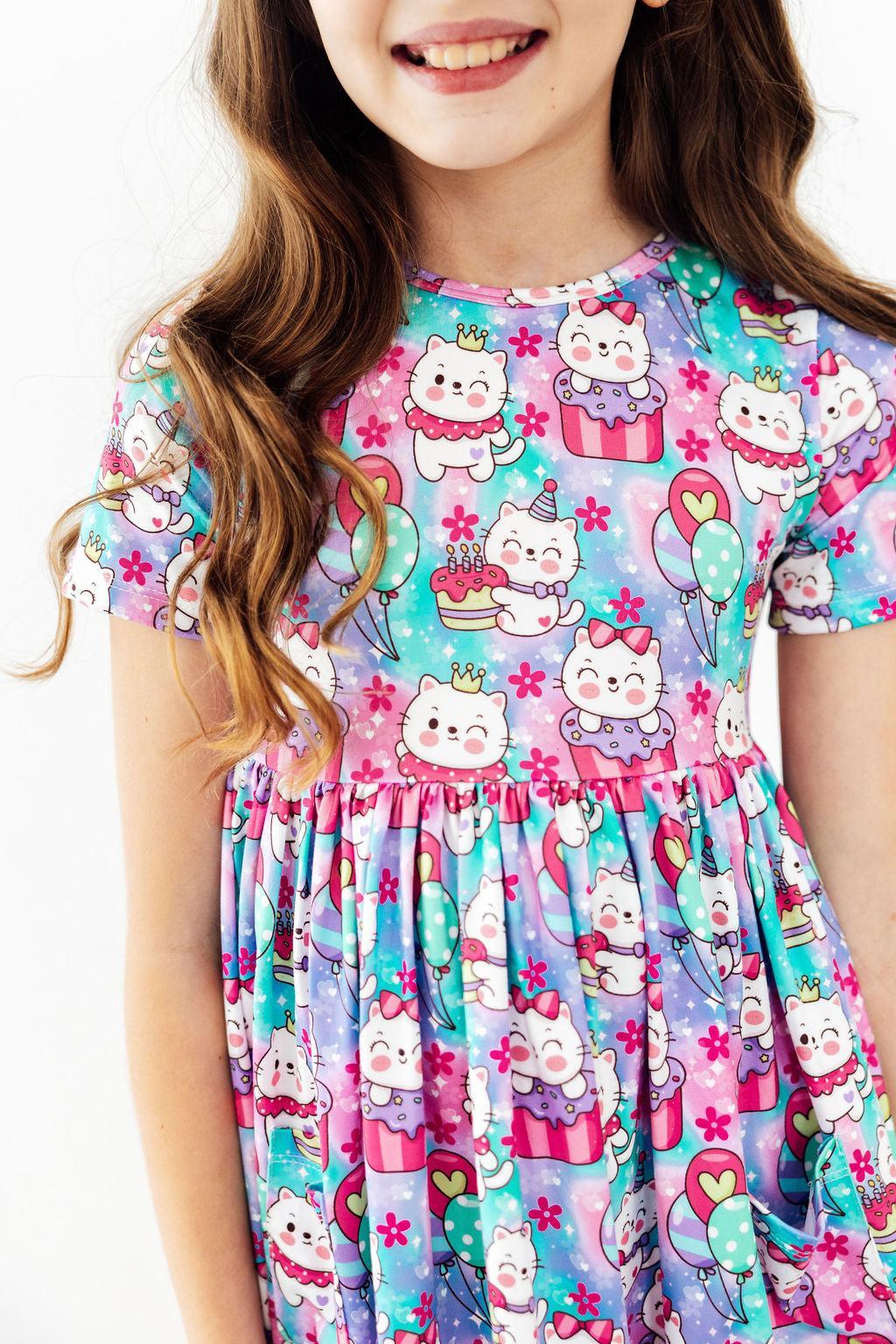 a girl wearing a dress with cartoon cats on it