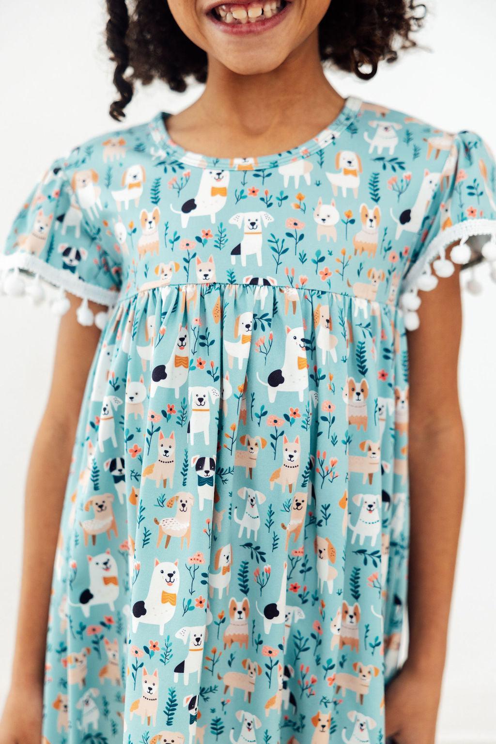 a girl wearing a dress with dogs and flowers