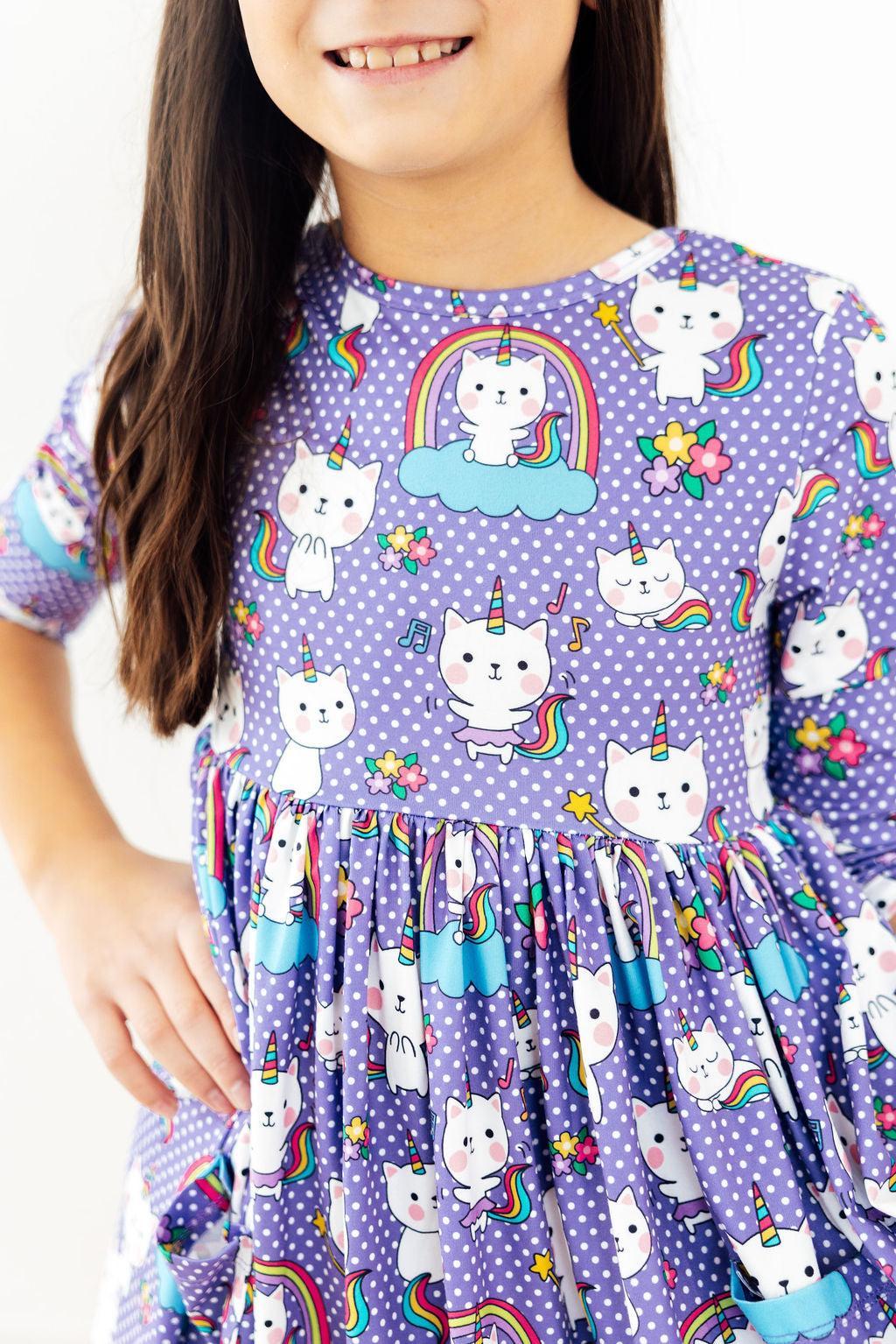 a girl wearing a purple dress with cats and unicorns