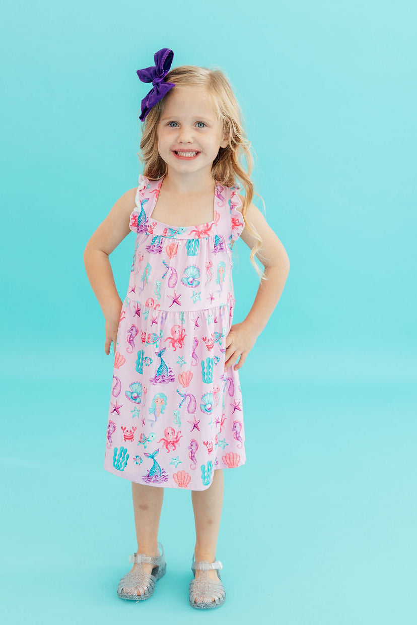 a girl wearing a pink dress and a purple bow
