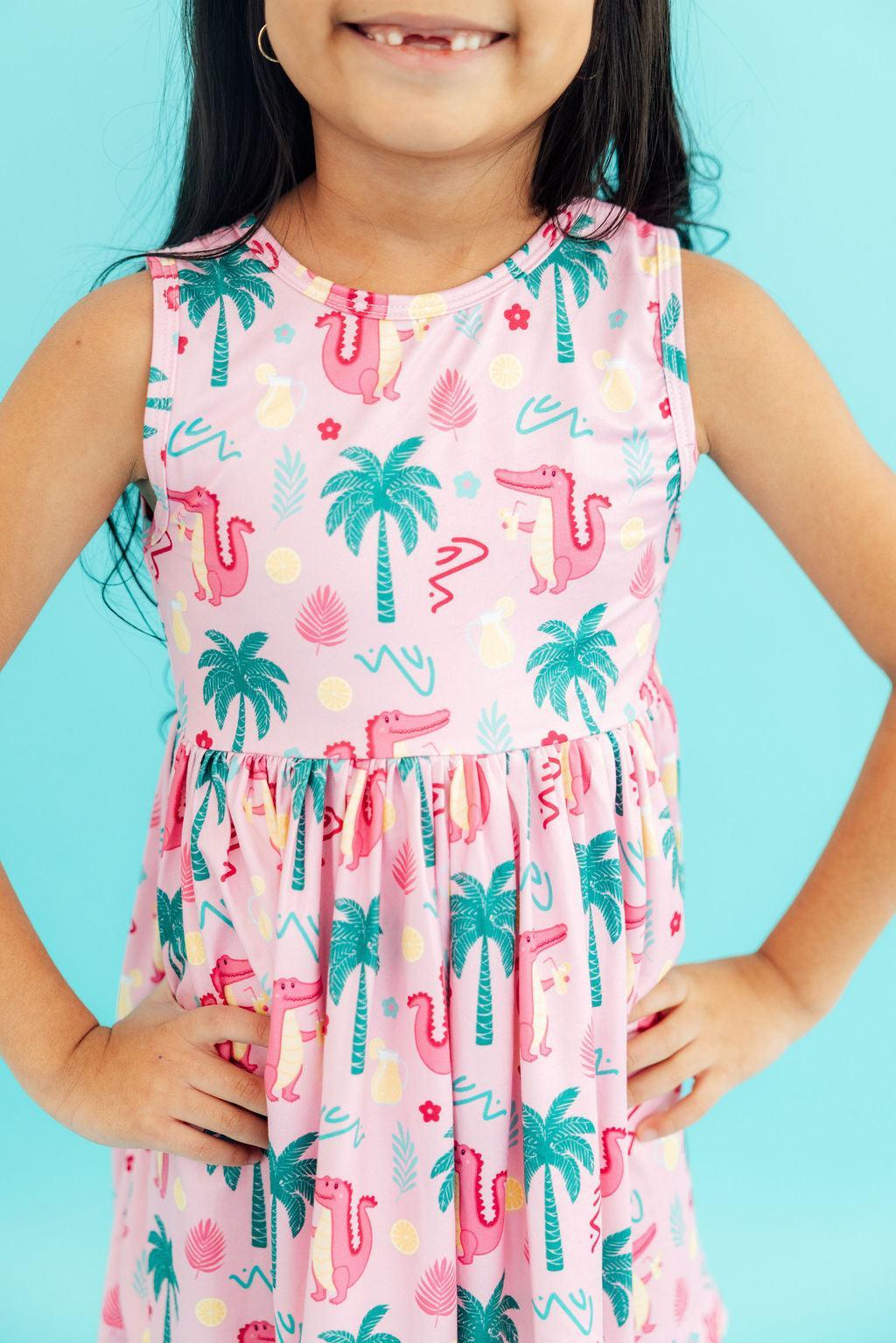 a girl wearing a pink dress with palm trees and crocodiles