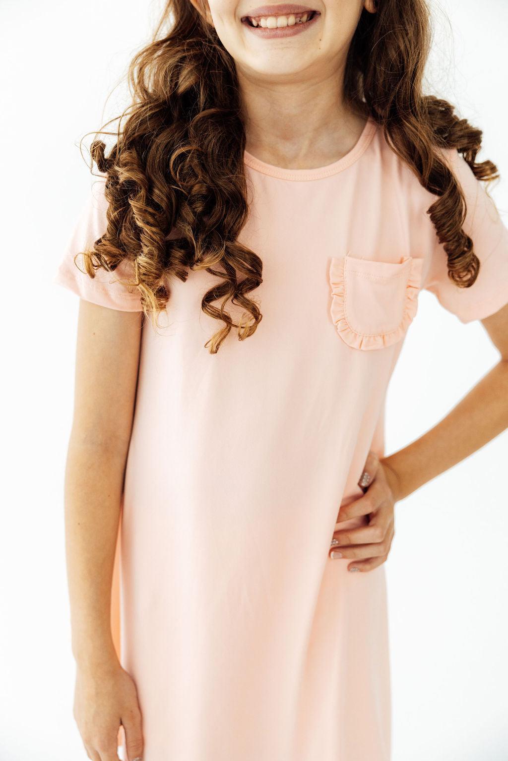 a woman with curly hair wearing a pink dress