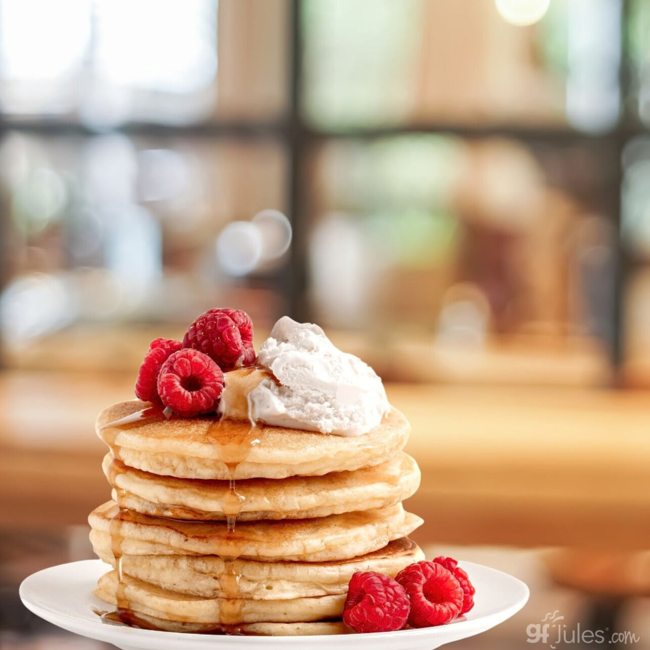 Stack of pancakes with raspberries and whipped cream on a plate, blurred background