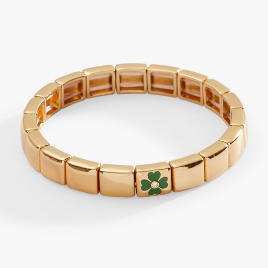 a gold bracelet with a green clover on it